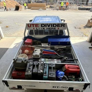 Open truck bed with various tools and equipment, labeled 'Ute Divider', on a construction site.