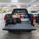 Truck bed with various items separated by a TubDivider including bags and groceries in a parking garage.