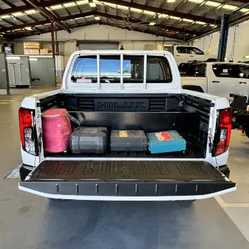 DivideUte divider system fitted in a HiLux tub, with tool cases and a red bag organised between the dividers.